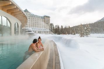 A couple enjoy the view from an outdoor hot tub at BASIN Glacial Waters Spa at Fairmont Chateau Lake Louise.
