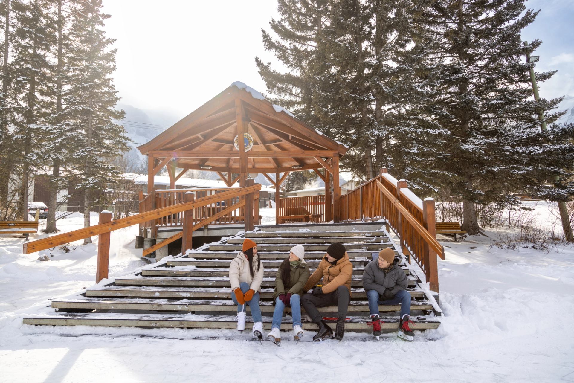 Canmore outdoor skating pond. Group of 4 friends putting their ice skates on