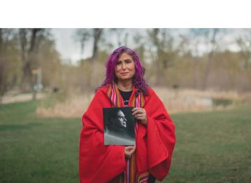 Indigenous women looking at camera while holding a black and white photo.