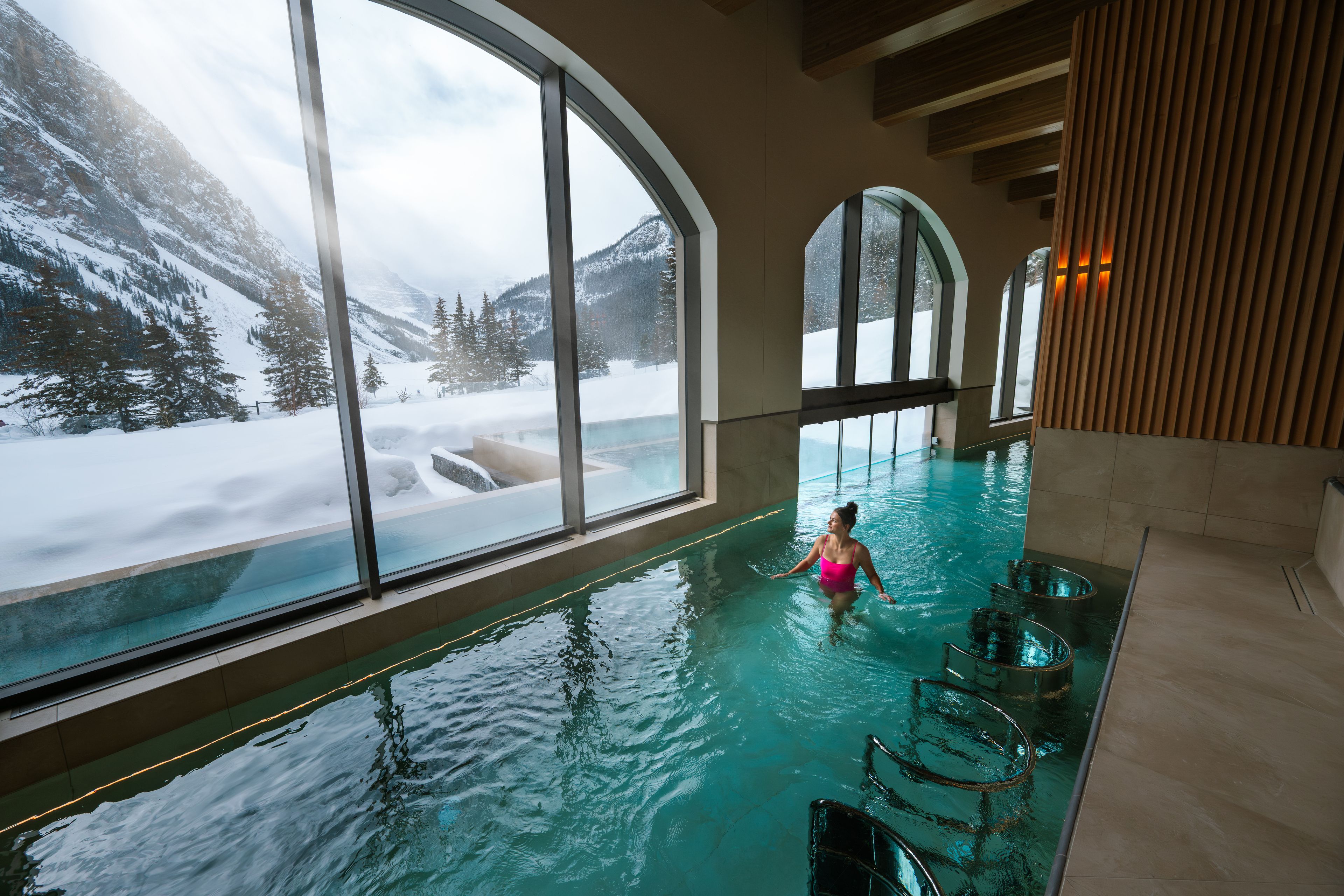 A woman walks through the therapeutic waters at BASIN spa, looking out at the Rockies.