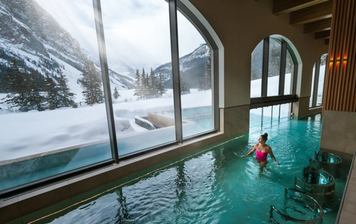 A woman walks through the therapeutic waters at BASIN spa, looking out at the Rockies.