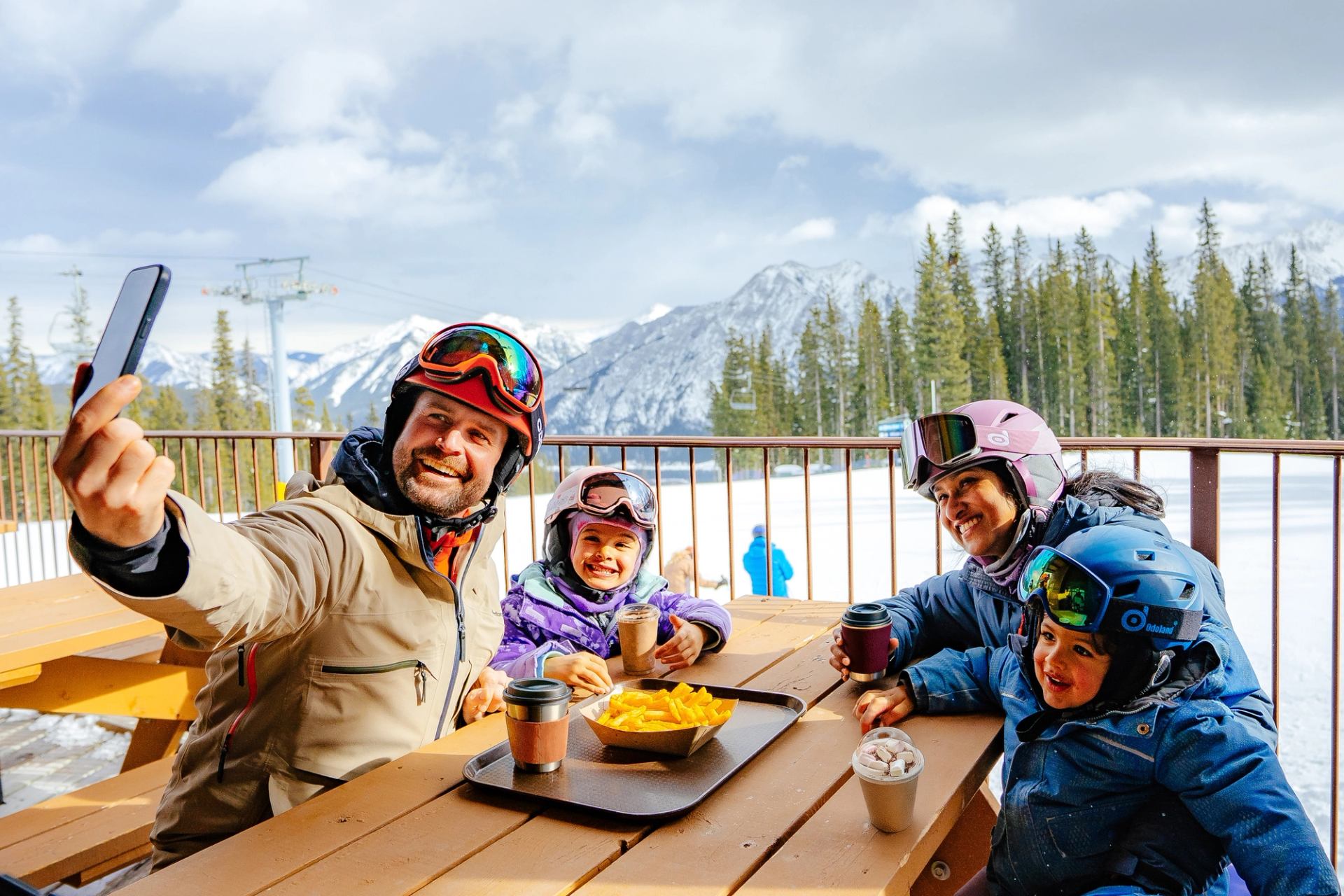 A family sits on the patio at Nakiska and takes a photo together.