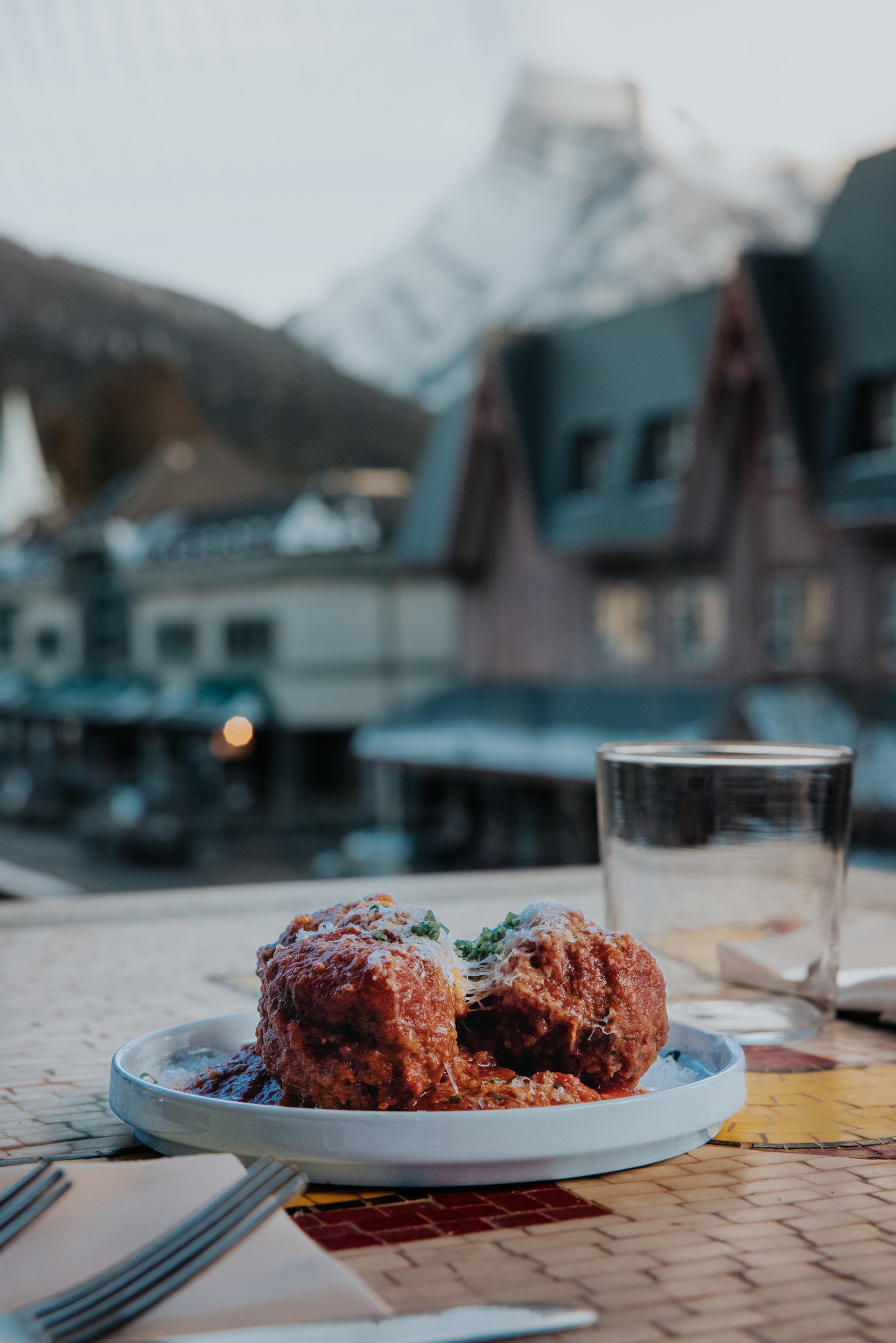 A closeup of food at Lupo in Banff, looking out a window at downtown.