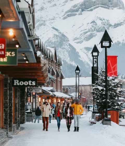 A group of visitors enjoying their coffee while walking in the Town of Banff in Banff National Park