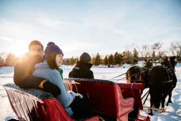 A couple being pulled on a horse drawn sleigh ride in the snow at Silver Skate Festival in Edmonton.