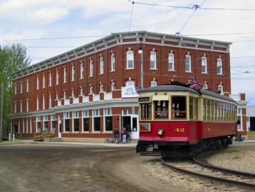 An old train car rolling by a fort hotel in a historic park.