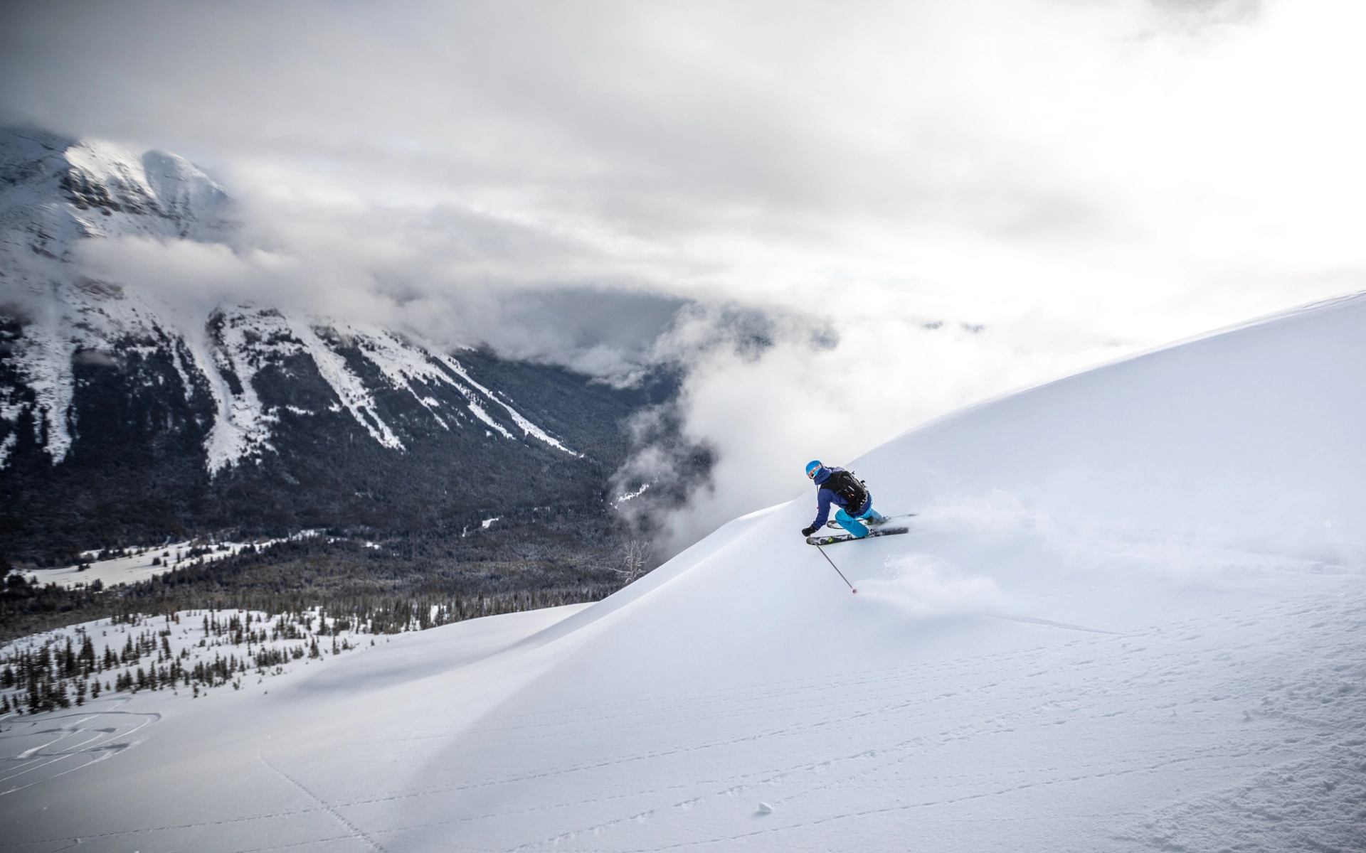 A skier on the open terrain with a mountain view while skiing Castle Mountain Resort