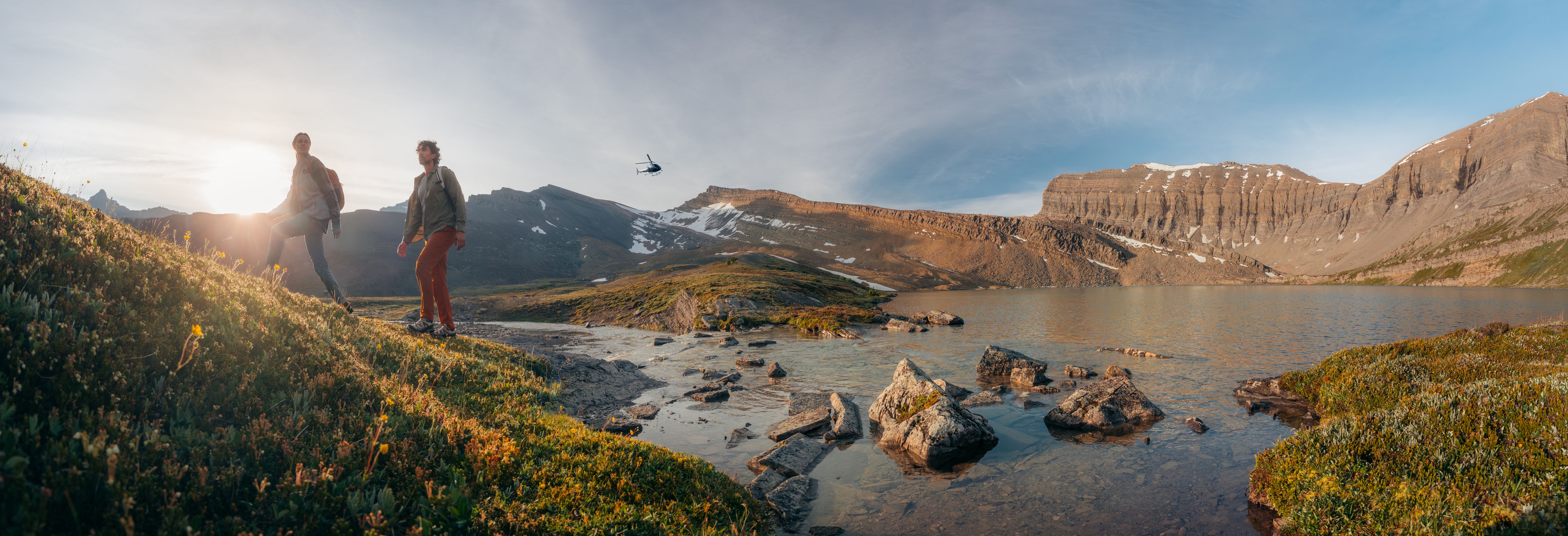 Two Heli Hikers beginning their hike with a helicopter taking off in background.