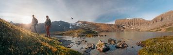 Two Heli Hikers beginning their hike with a helicopter taking off in background.