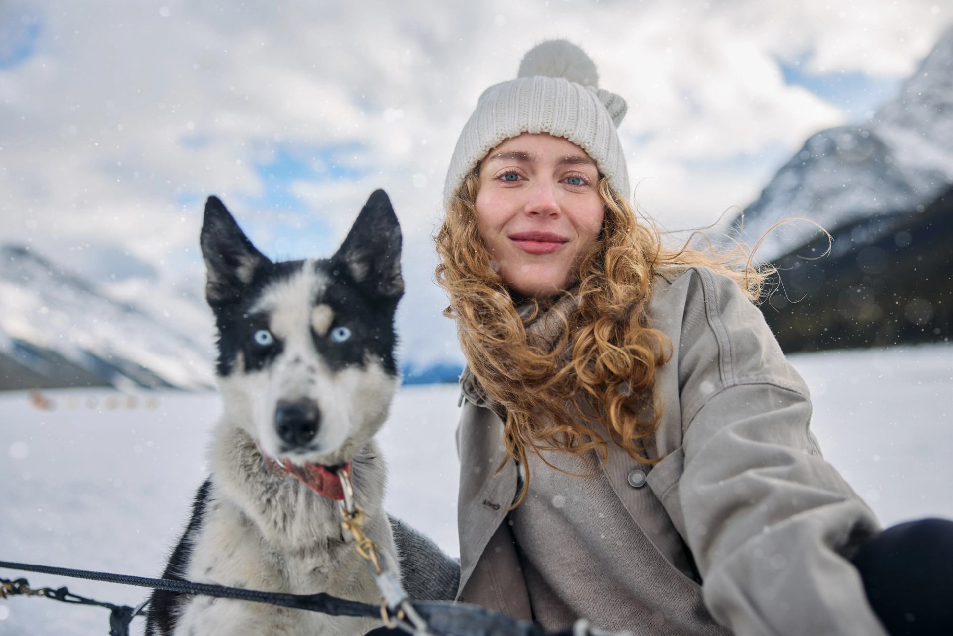 A woman posing in front of the Canadian Rockies with a sled dog in Spray Lakes, Kananaskis.