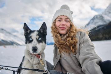 A woman and a sled dog on a sunny winter day in Spray Lakes in Alberta's Kananaskis Country.