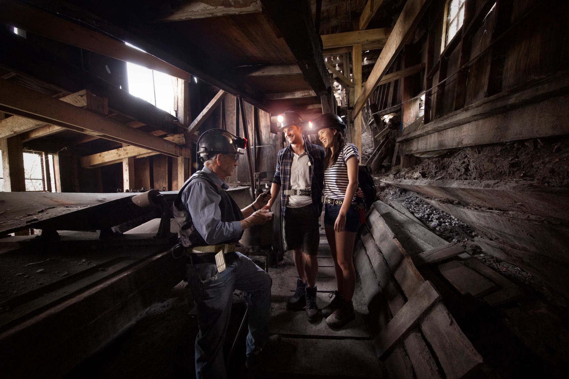 Man and woman wearing mining hats and exploring Atlas Coal Mine with a guide.