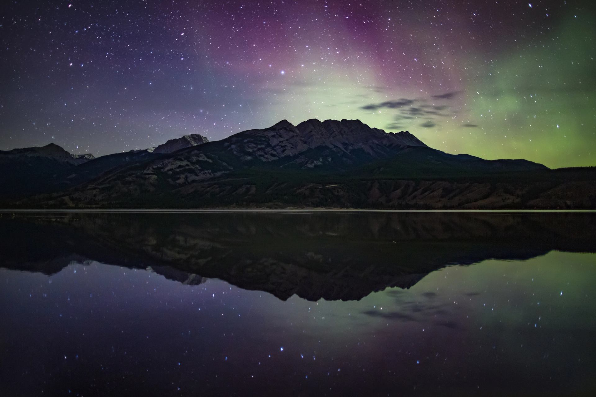 Starry skies and northern lights over Jasper Lake in Jasper National Park.