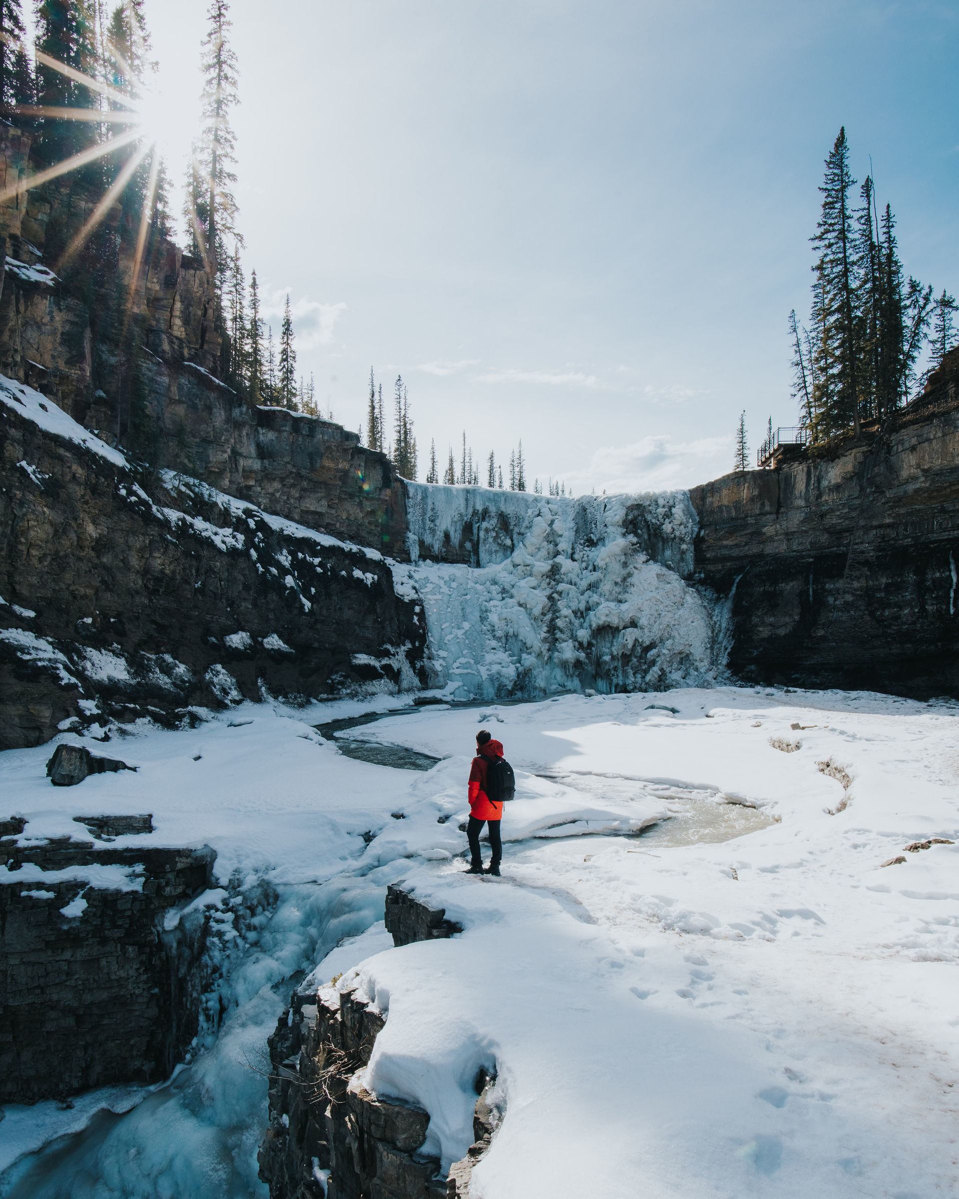 A man stands at the base and admires the frozen waterfall at Crescent Falls in Clearwater County, Nordegg