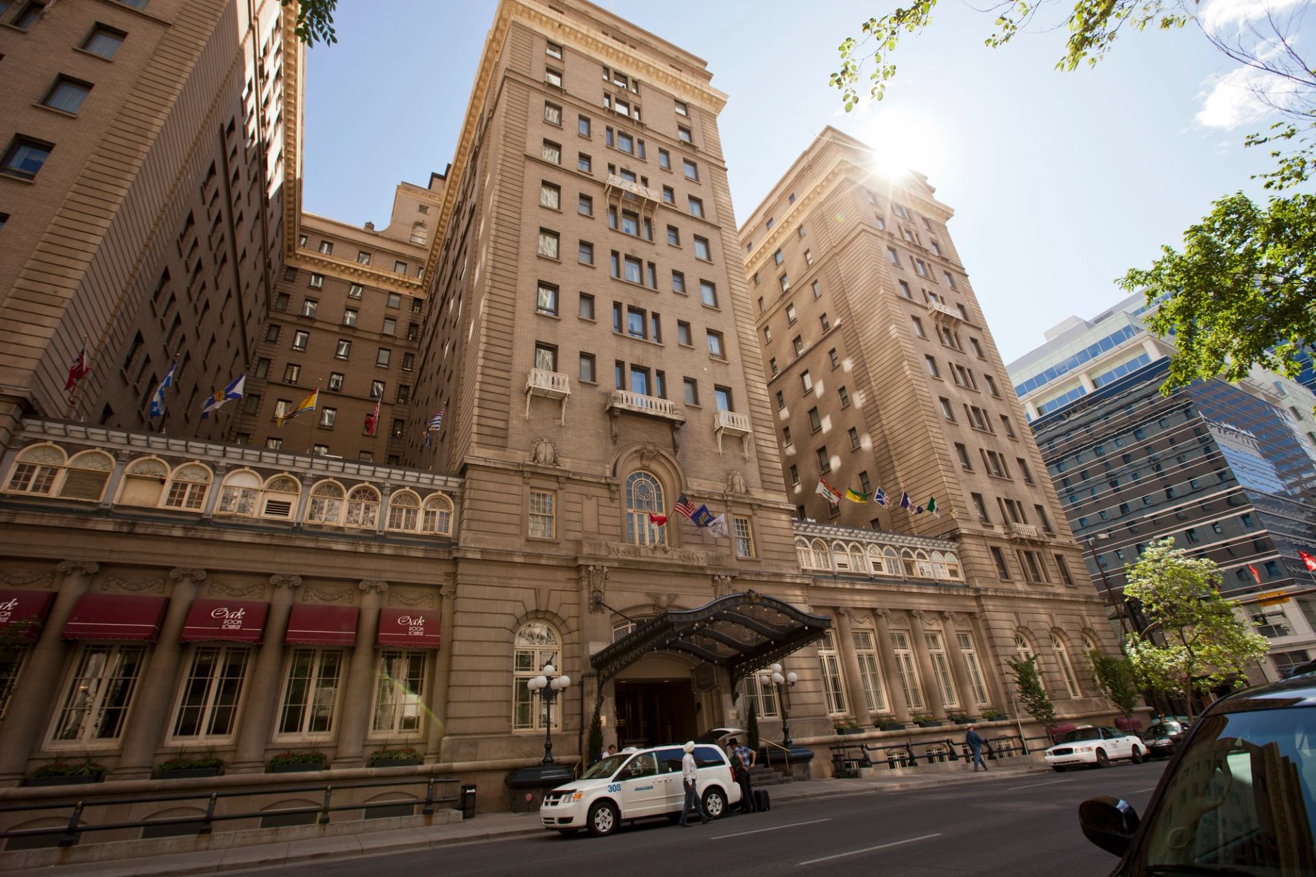 Historic and imposing stone hotel dominates the the street as the sun shines from over the top of the building