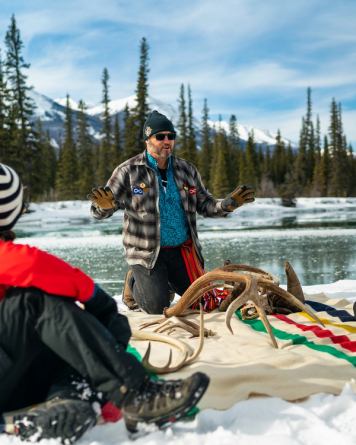People sitting by river learning about antlers from Jasper Tour Company guide.