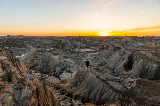 A person hiking at Dinosaur Provincial Park at sunset.