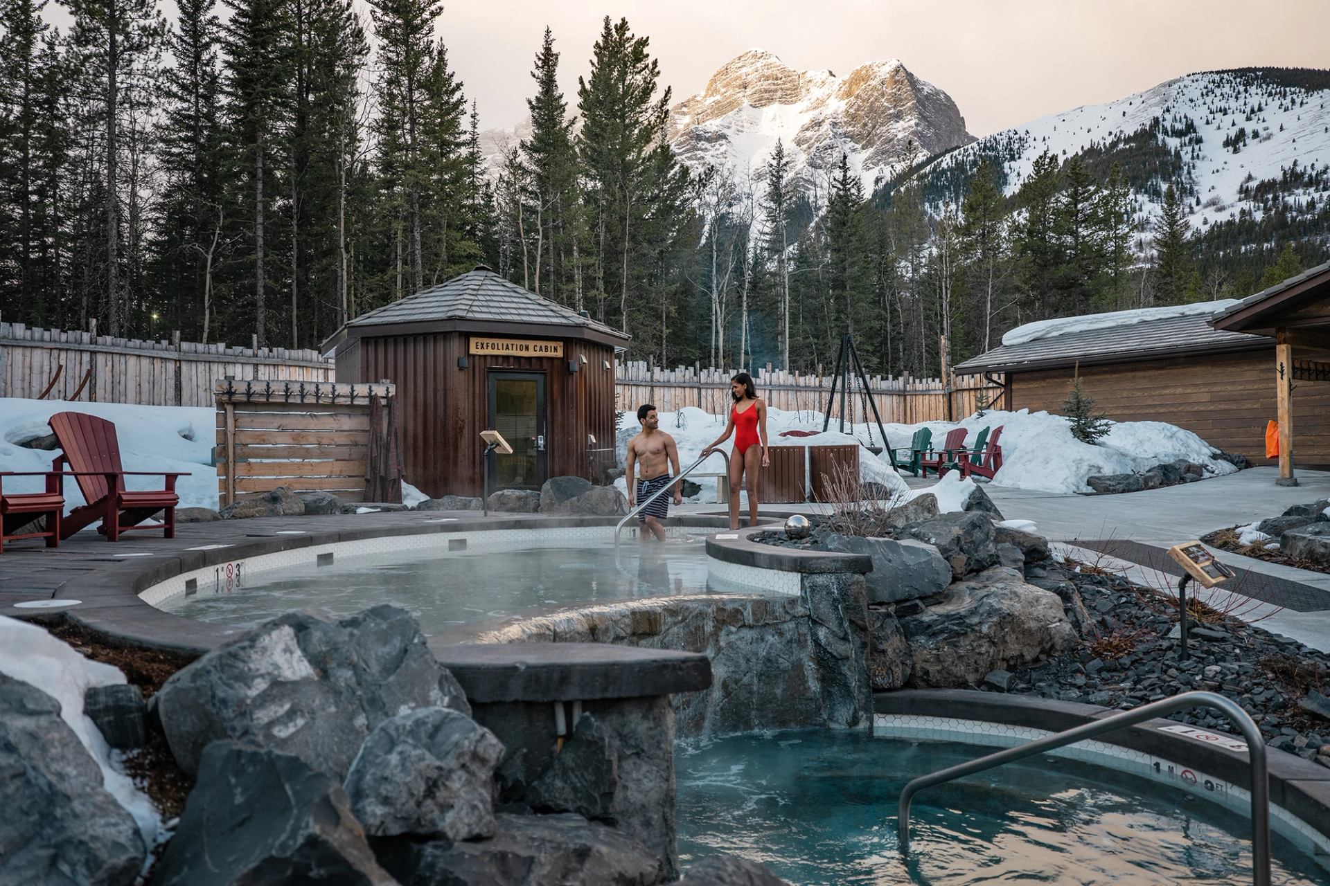 A couple entering the hydrotherapy pools at the Kananaskis Nordic Spa, with mountains in the background.