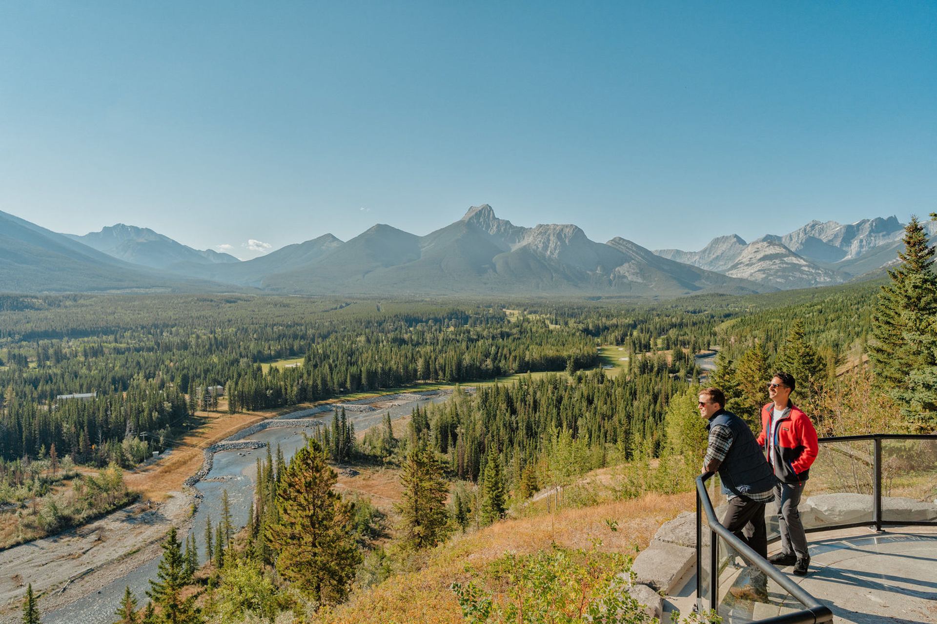 Couple looking out over mountains and a river from a viewpoint platform.