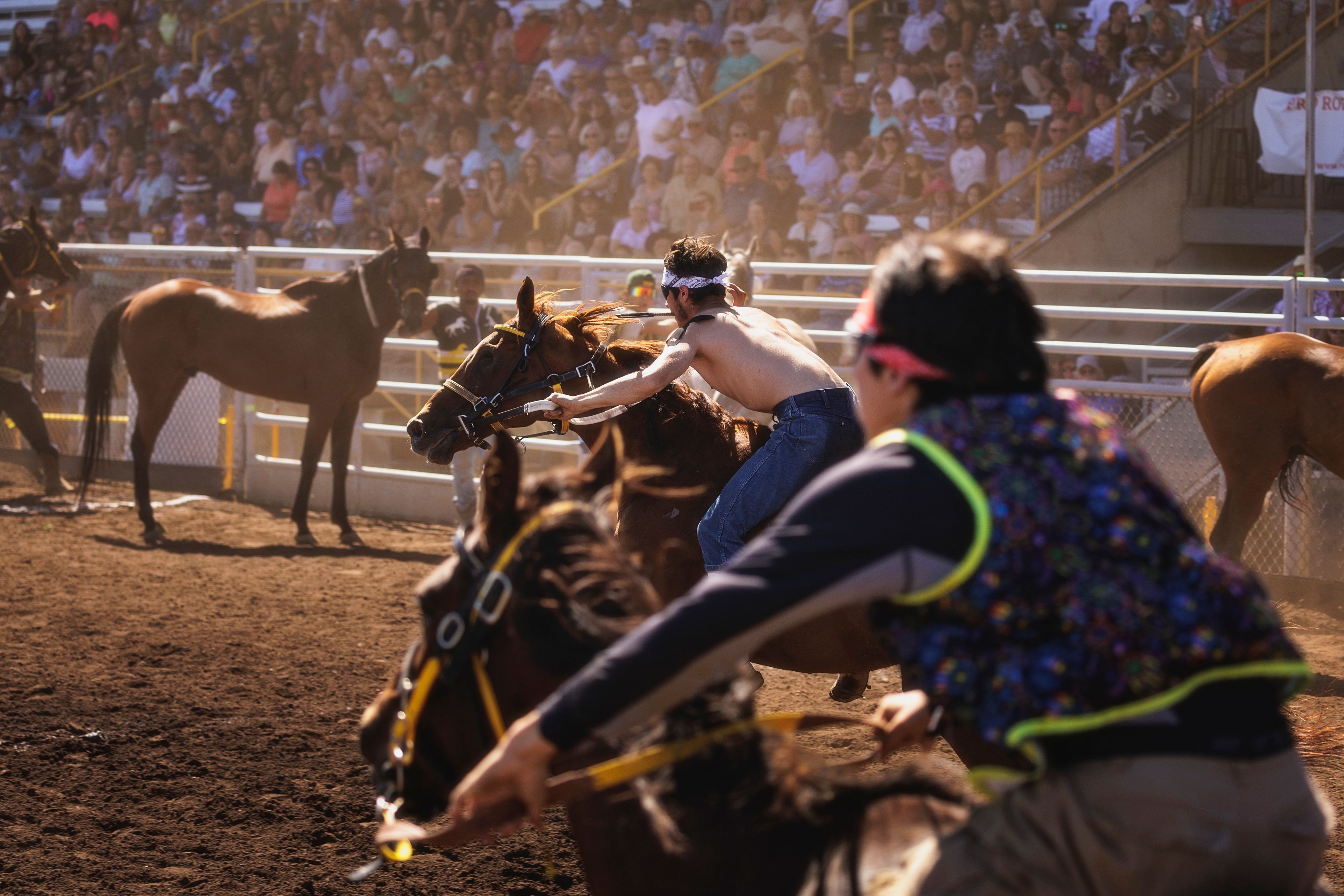 Two riders thunder toward the exchange zone, where teammates stand ready.