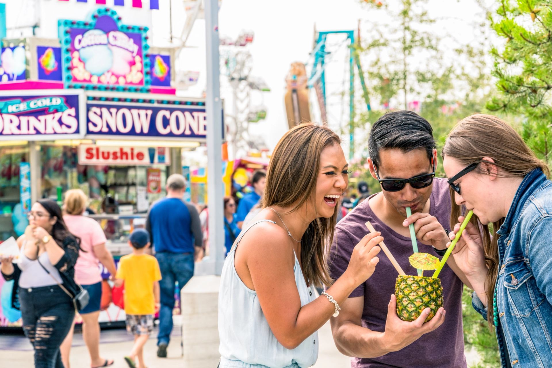 Friends share a drink from a pineapple at the midway