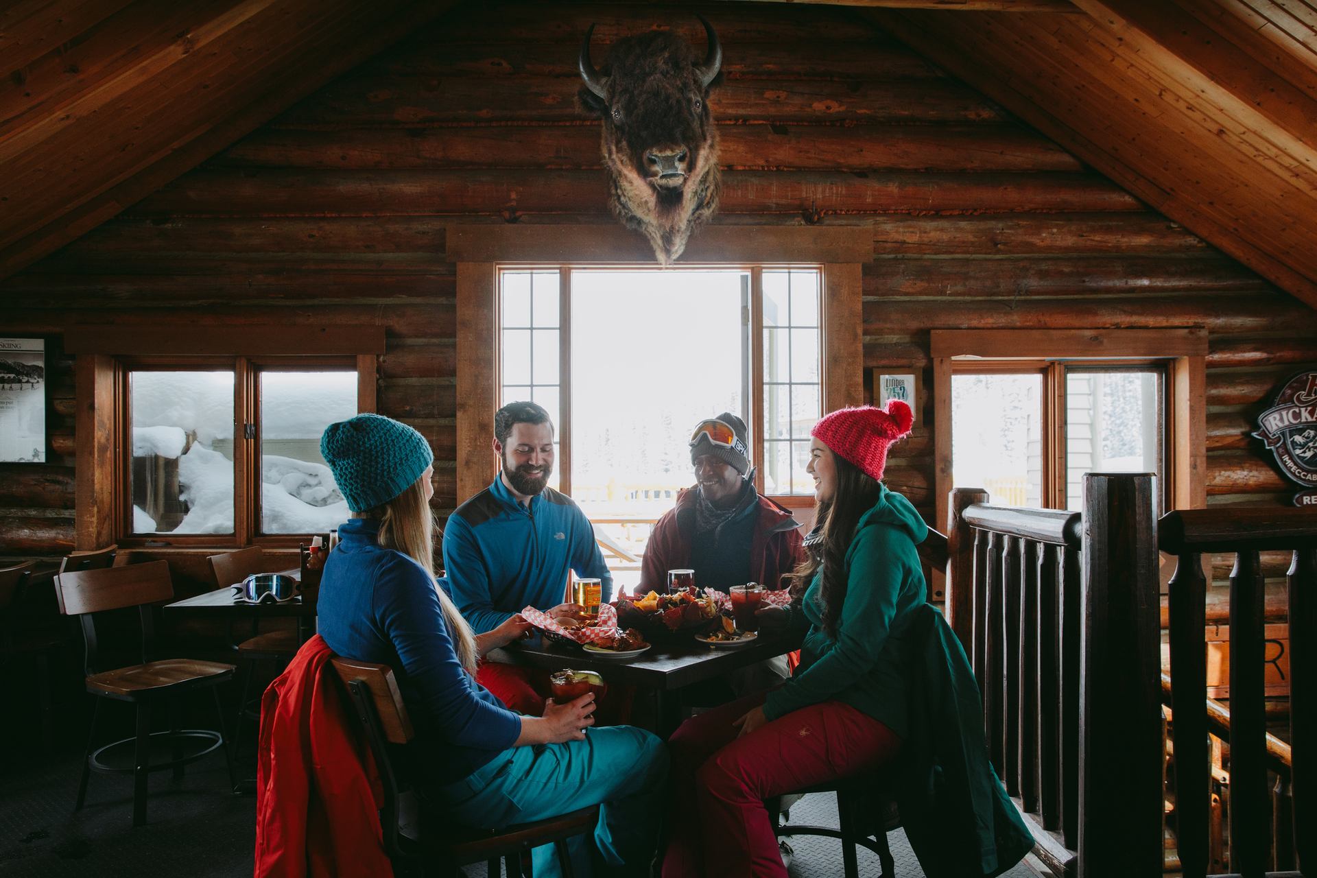 A group of friends enjoying drinks and appetizers at Mad Trapper’s at Sunshine Village in Banff National Park