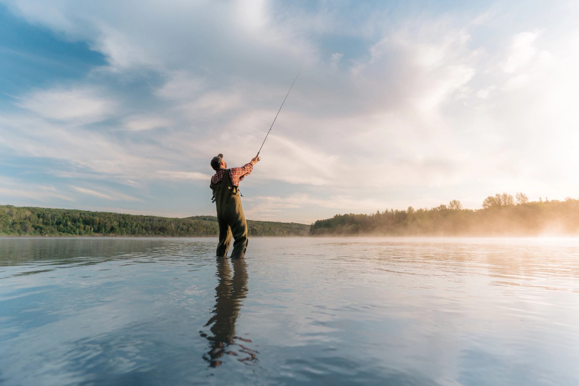 Man standing in the water fly fishing in the Athabasca River.