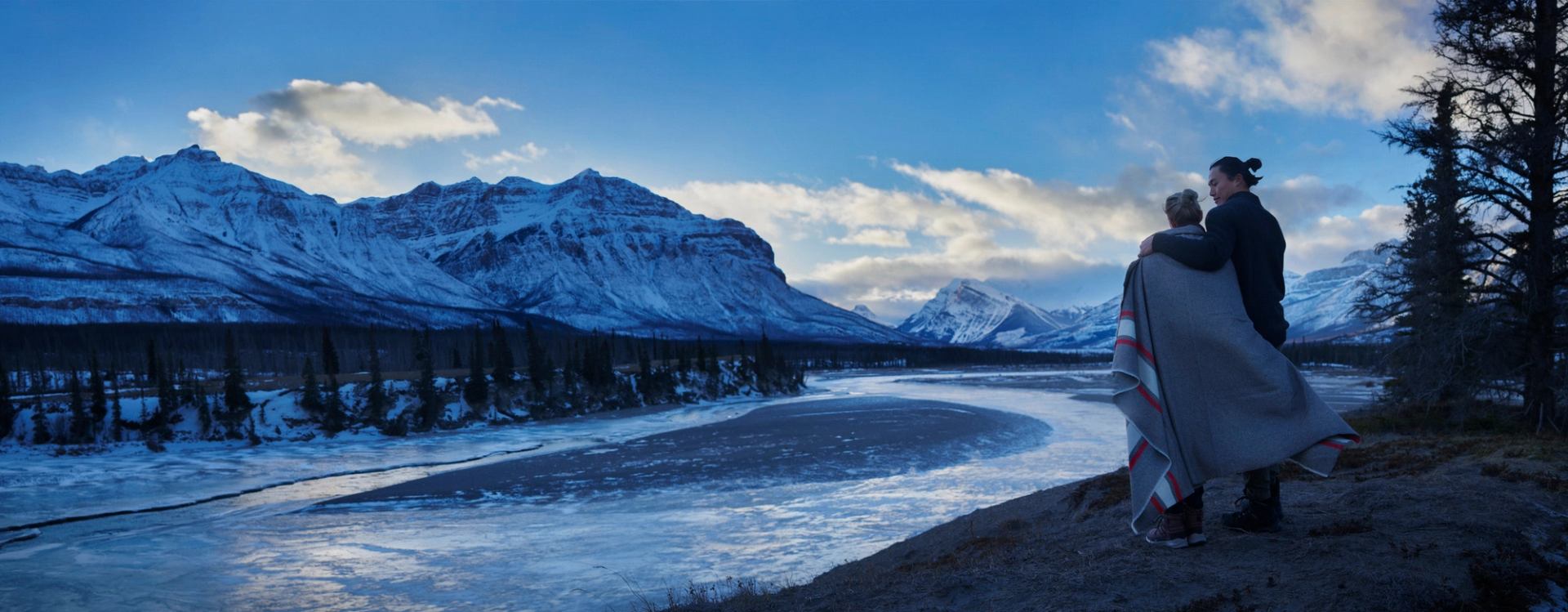 Couple taking in the view of the Alberta mountains with a blanket wrapped around them.