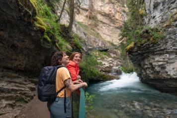 A couple takes a moment to pause and looking at the canyon while they are walking along the boardwalk at Johnston Canyon