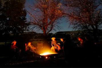 People sitting around a campfire under the starry night sky.