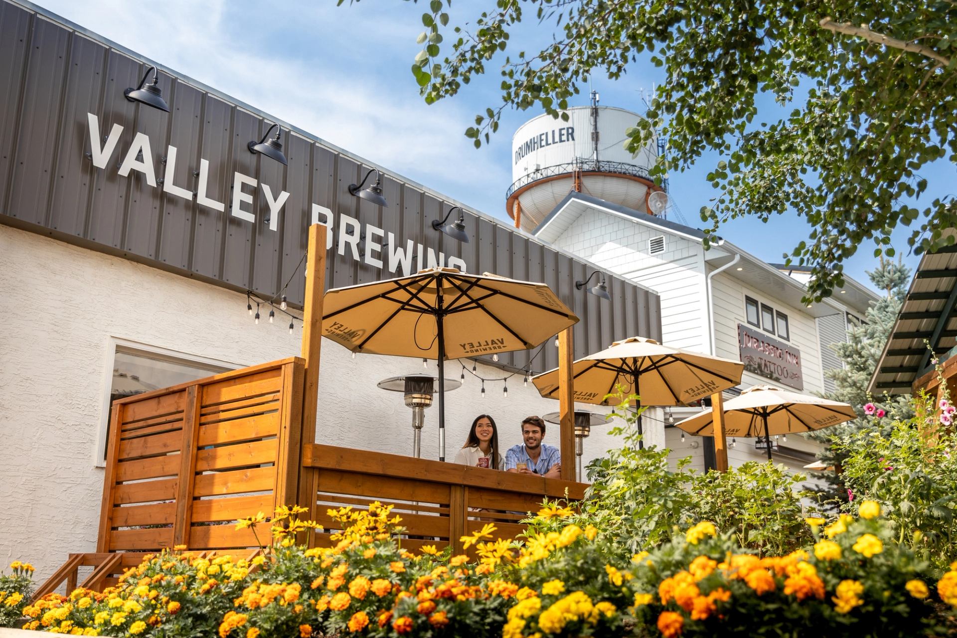 A couple sit at an outdoor patio with a water tower in the background at Valley Brewing in Drumheller.