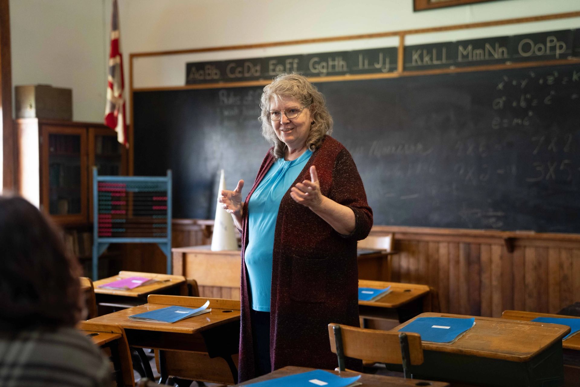 A tour guide shows a group around a historic schoolhouse.