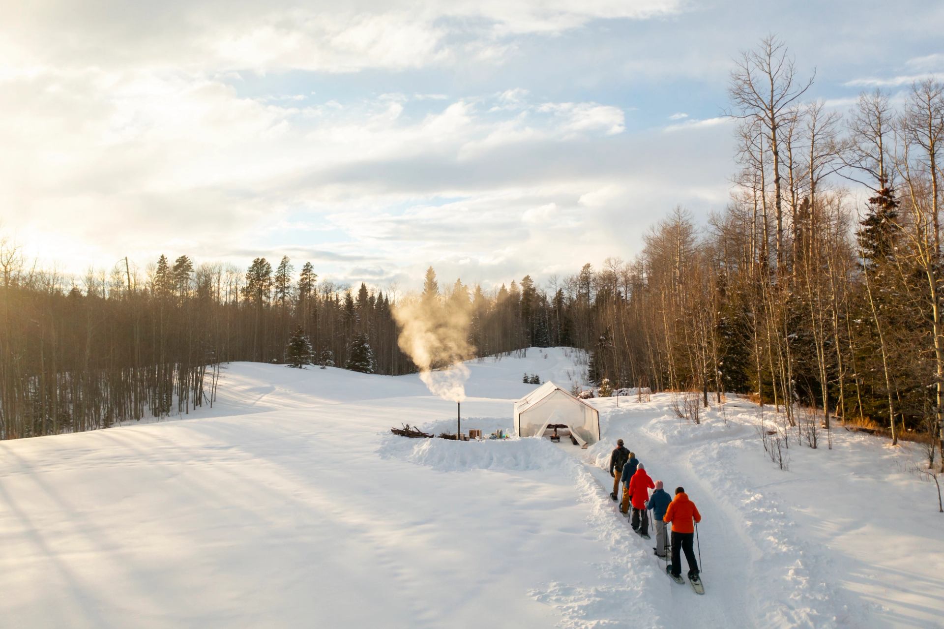 An aerial view of the group snowshoeing their way to the stargazing tent on the gudied walk as the sunsets in the background.