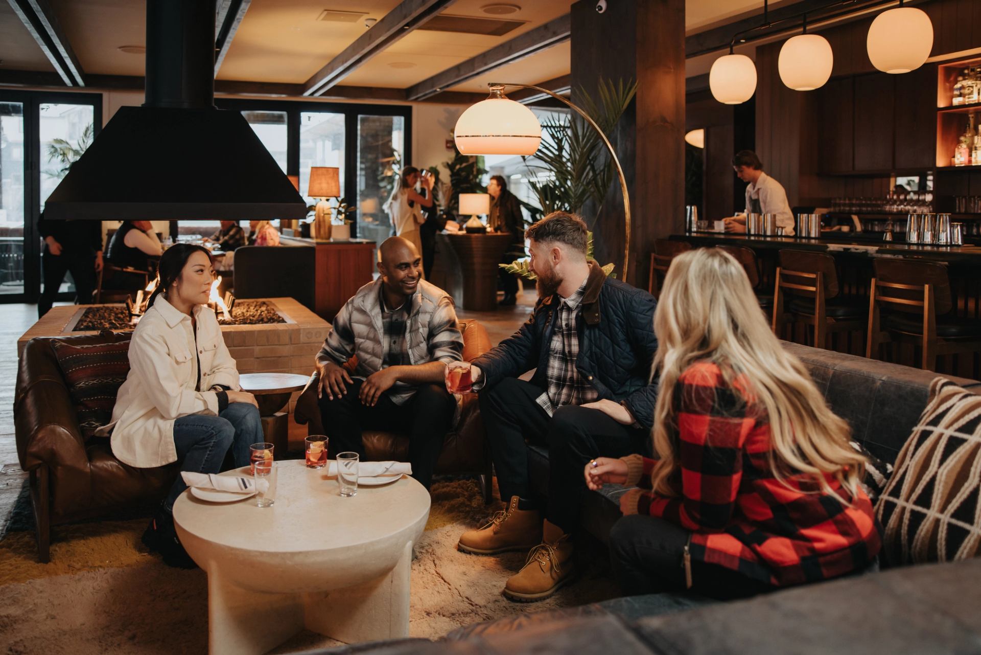 Four friends sit around a table in the cozy, mid-century modern-style Bridgette Bar in Canmore.