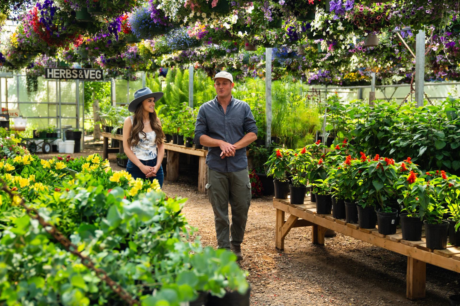 Hailey Benedict interviewing the owner of the Saskatoon Farm as they walk through vibrant plants.