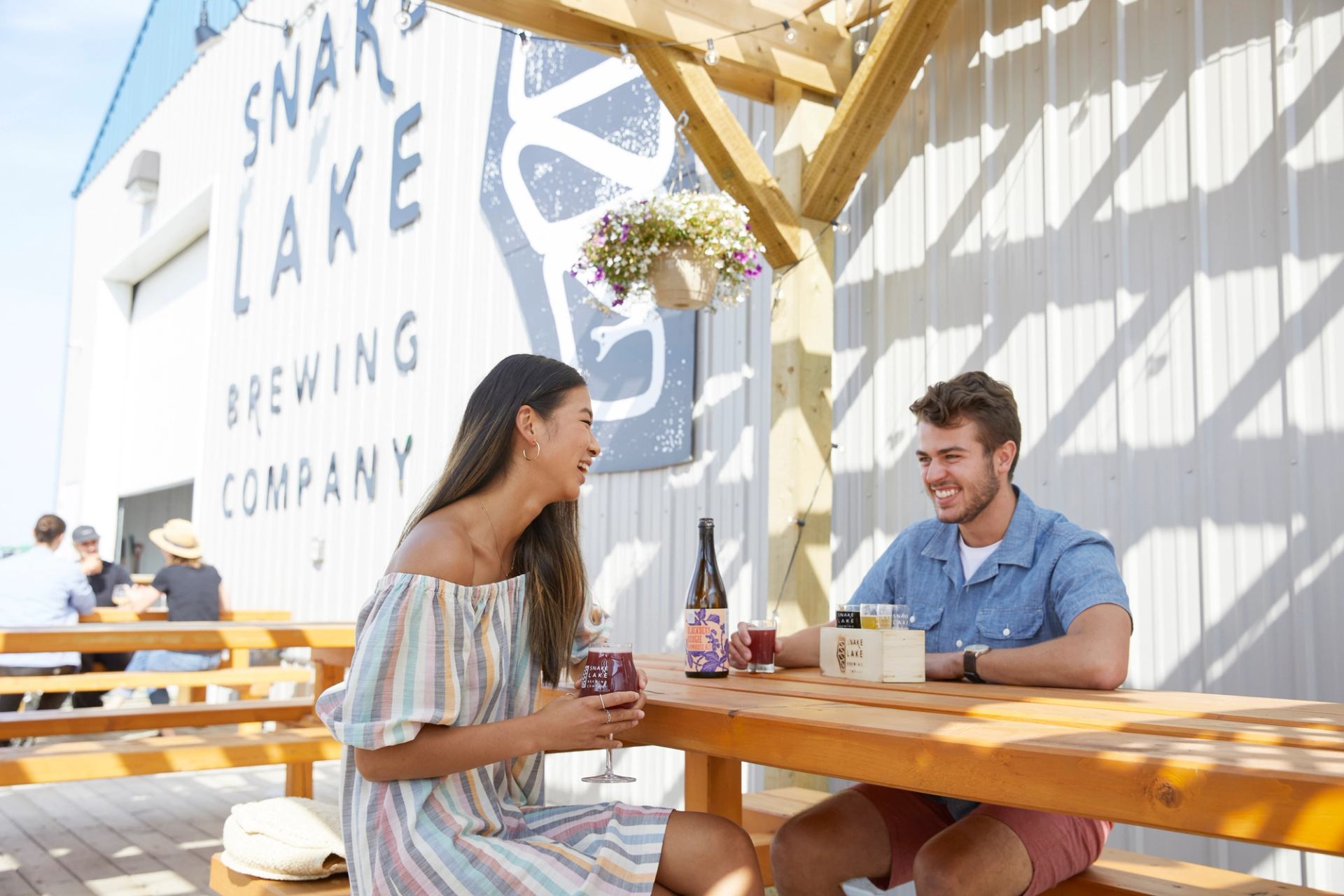 A man and woman sit at a picnic table drinking samples of beer outside Snake Lake Brewing Company.