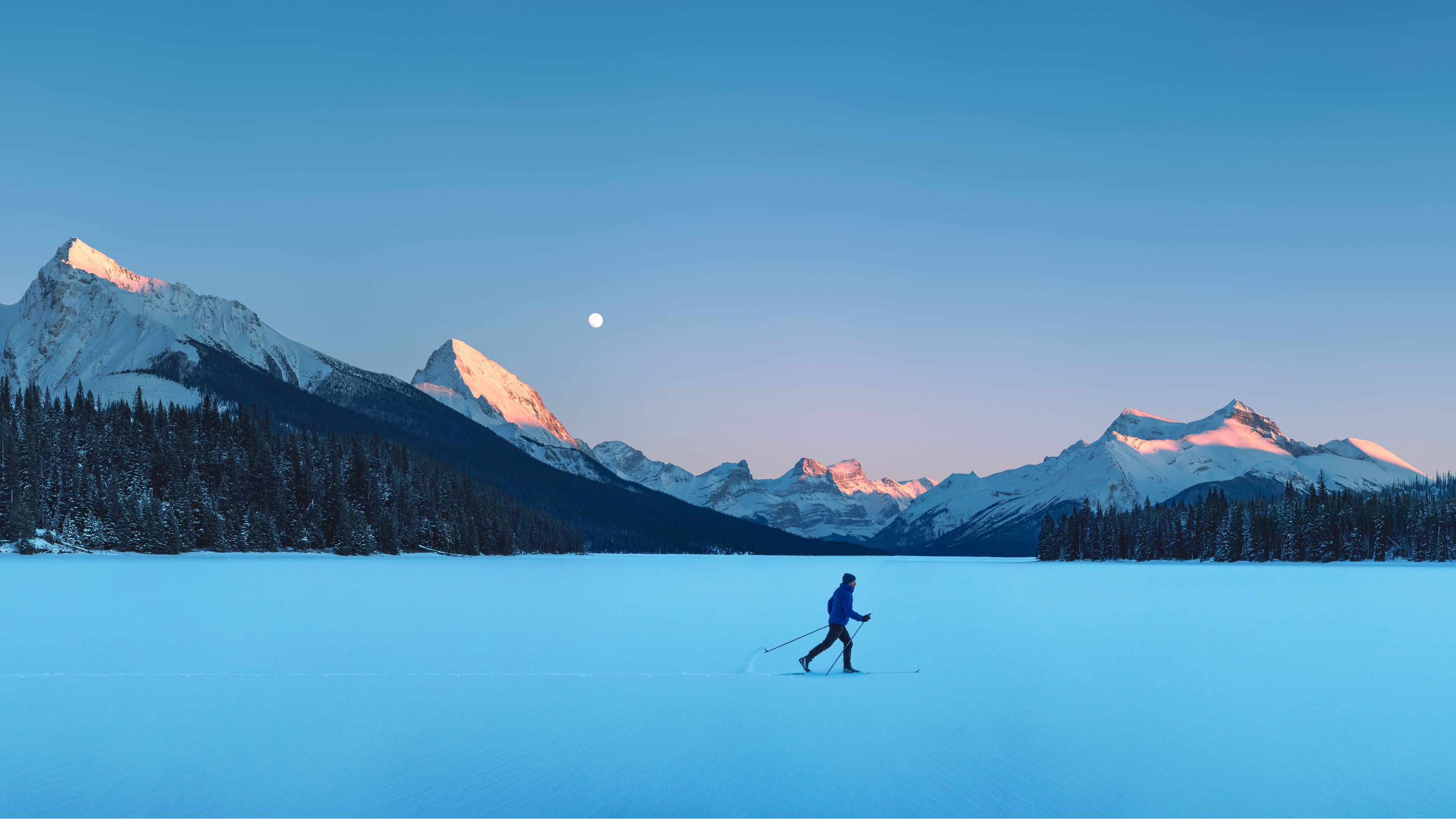 A man cross-country skiing on Maligne lake.