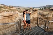 A couple takes photos in front of the hoodoos near Drumheller.