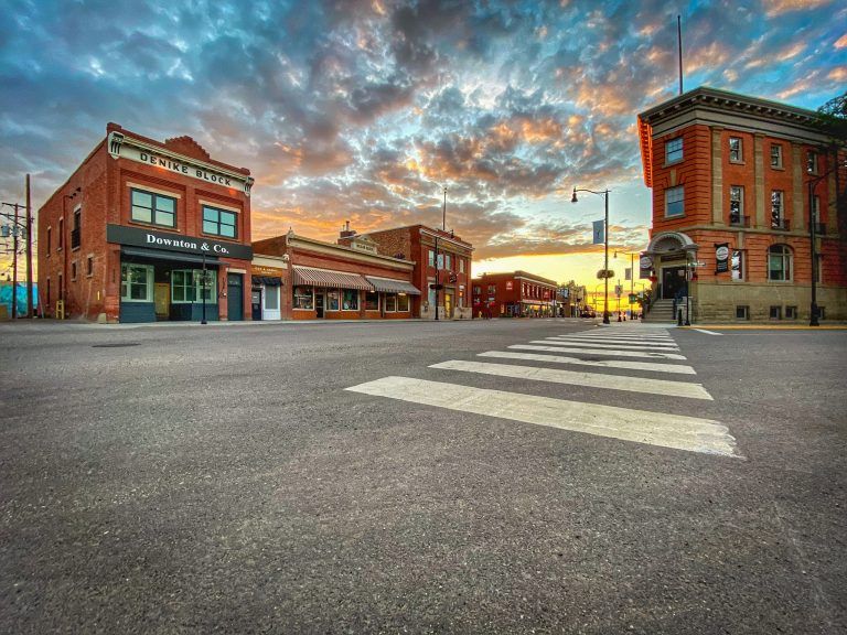 A charming small town street with red brick buildings and a colourful sunrise.