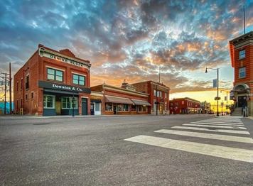 A charming small town street with red brick buildings and a colourful sunrise.