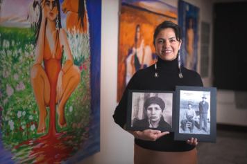 Woman smiling and holding two historical images in an art gallery.