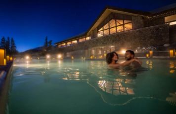 a couple in a hottub in front of the Fairmont Spa Jasper Park Lodge
