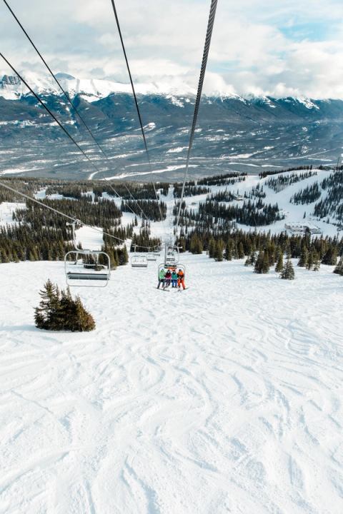 A group of skiers and snowboarders ride the chair lift before skiing down Marmot Basin in Jasper.