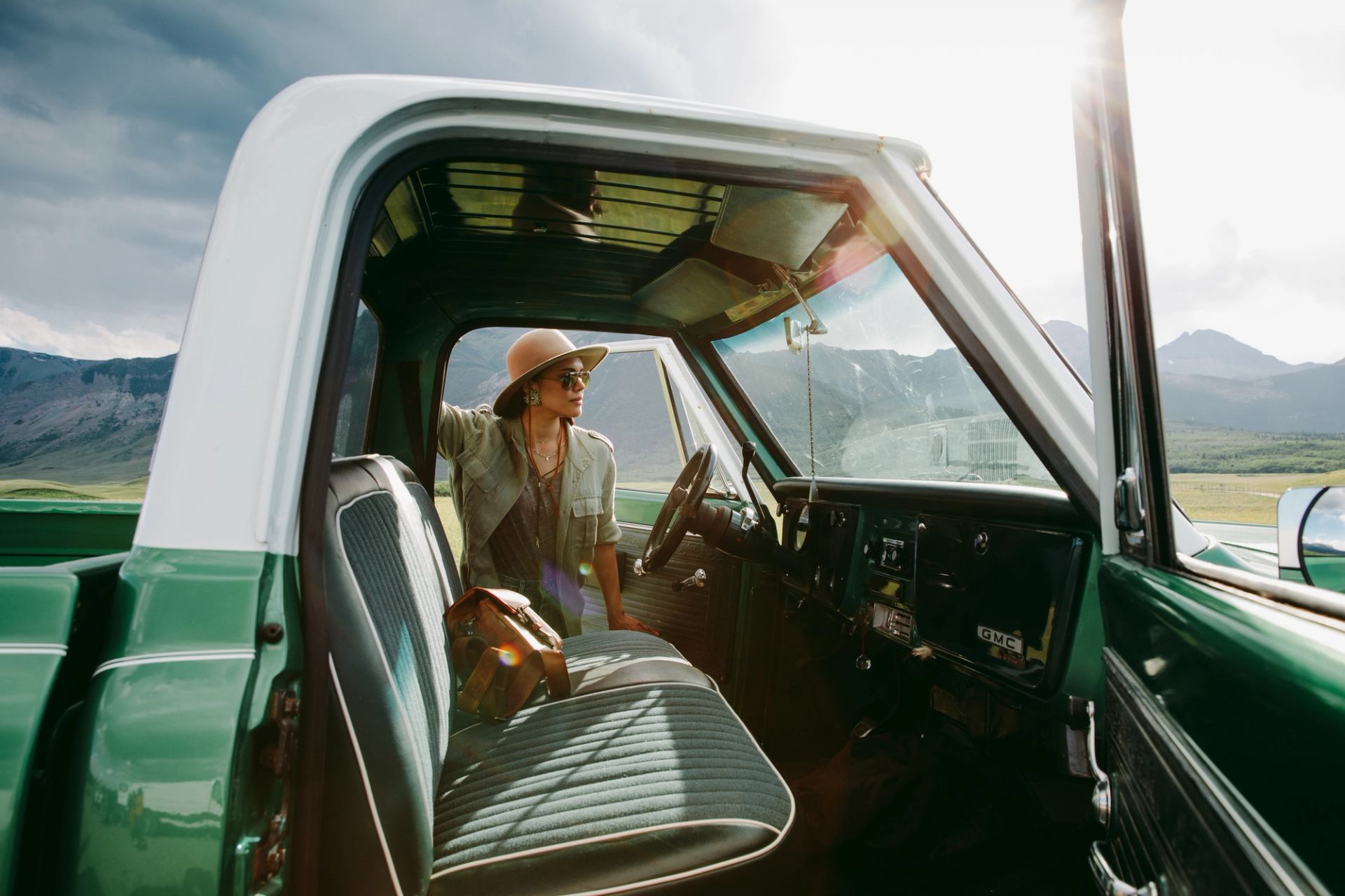 A woman stands beside an open car door while travelling in the mountains.