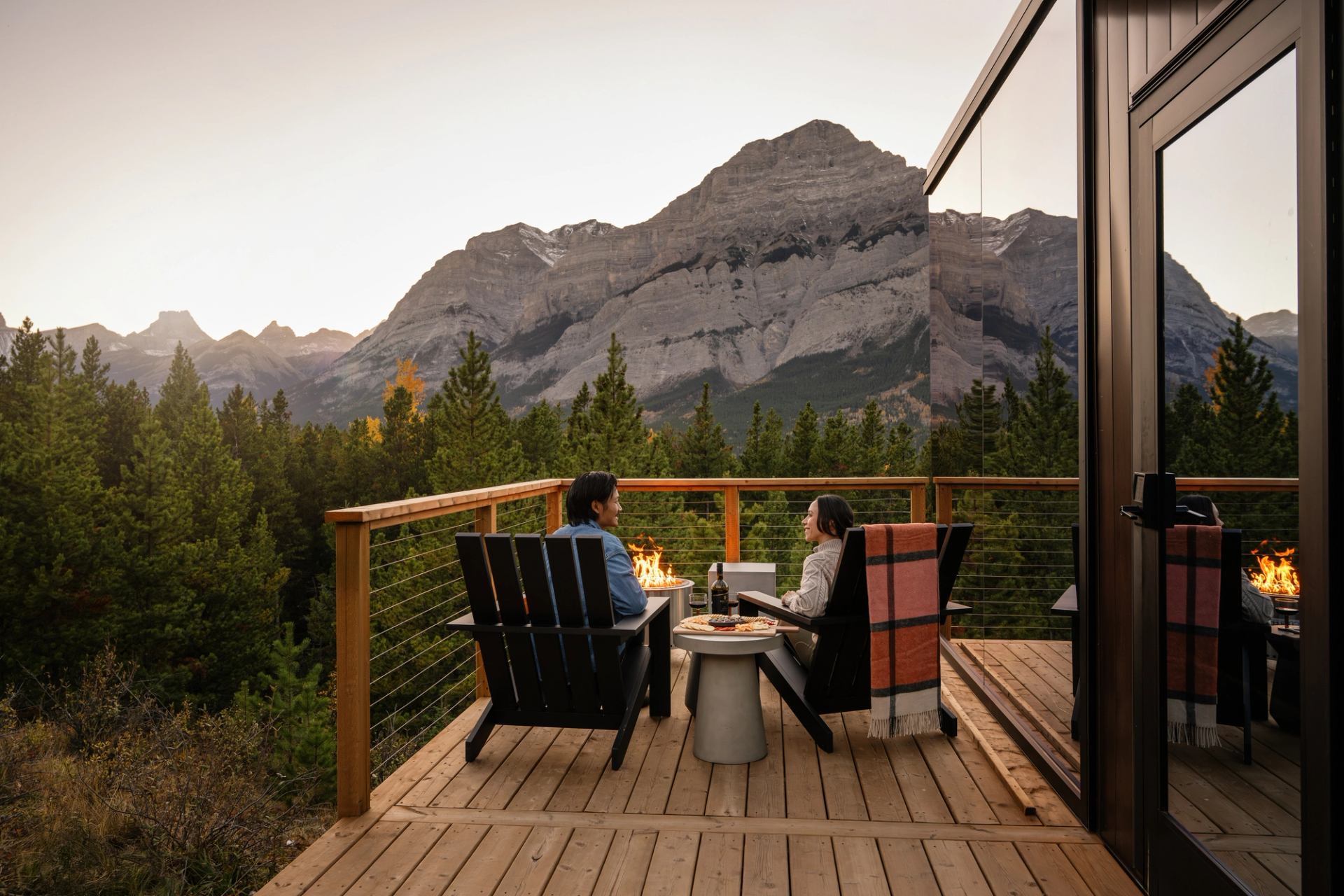 Couple sitting on a deck enjoying the mountain view at Skyridge Glamping in Kananaskis Country.