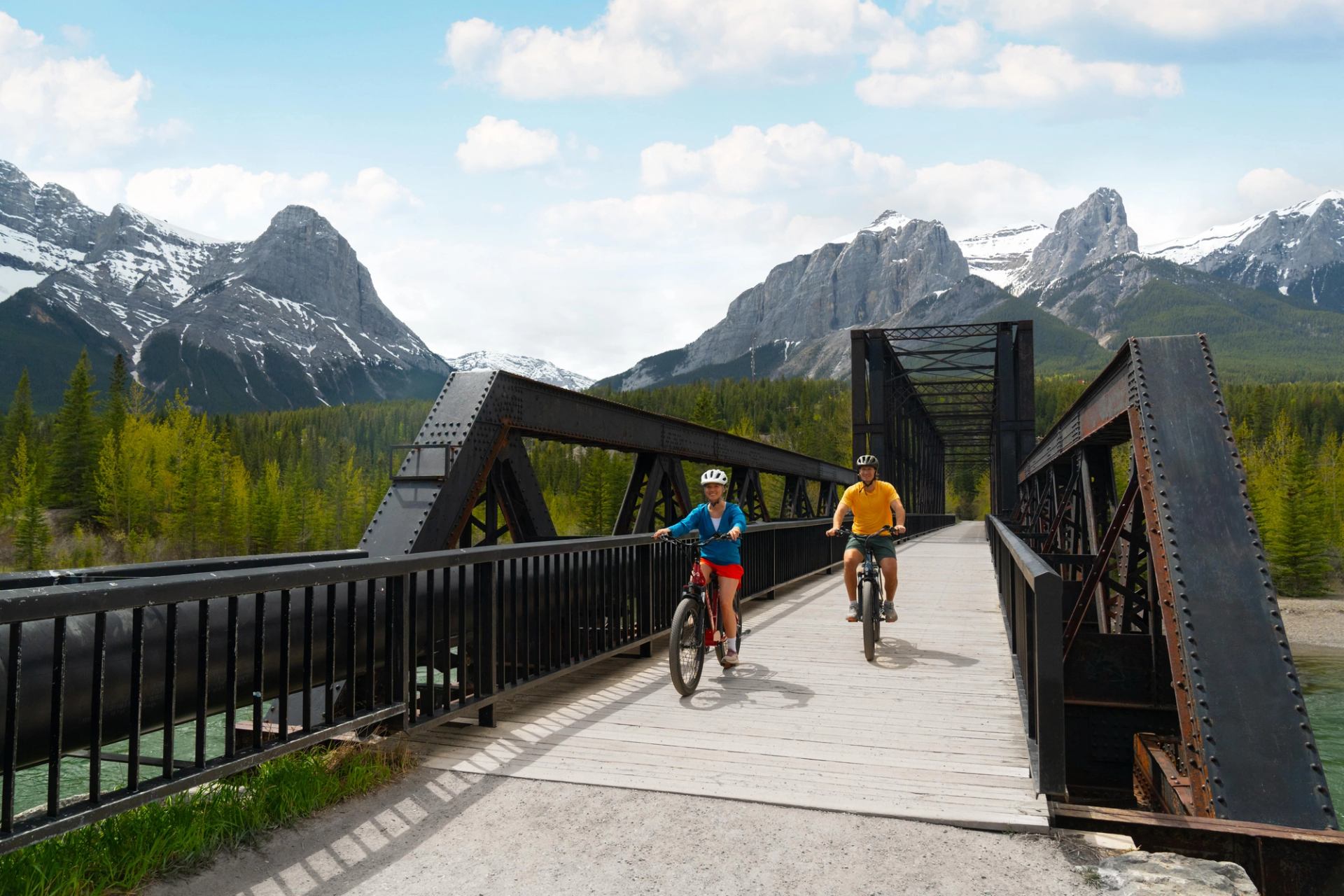 A couple riding their bikes across the engine bridge in Canmore