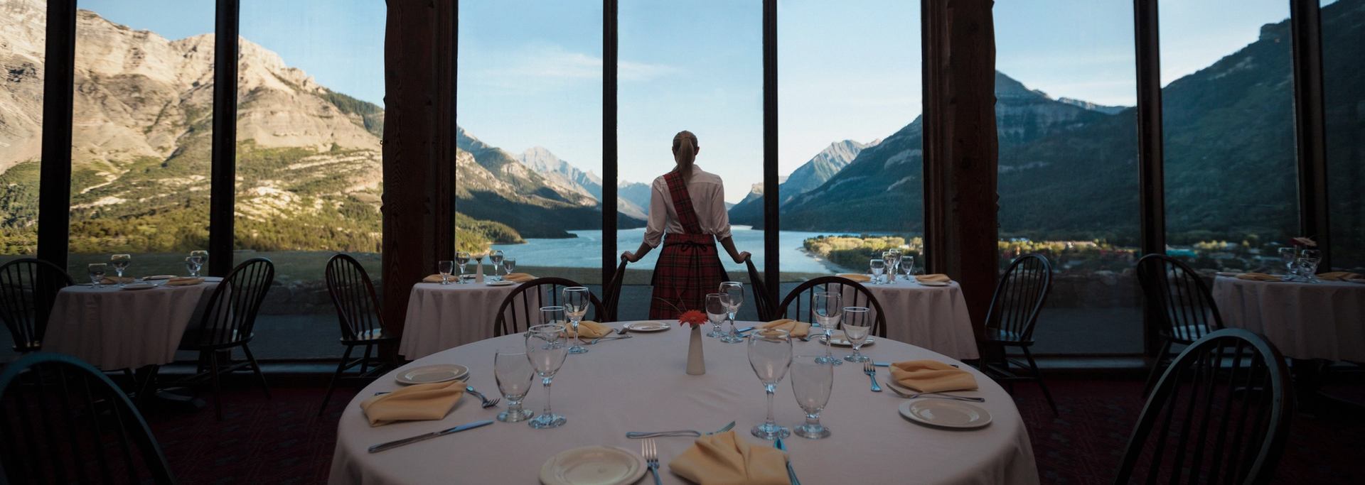 Waitress looking out restaurant windows to the lake at the Price of Wales Hotel in Waterton.
