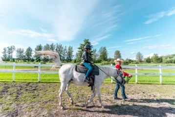 cowgirl leading child on horseback walk