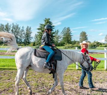 cowgirl leading child on horseback walk