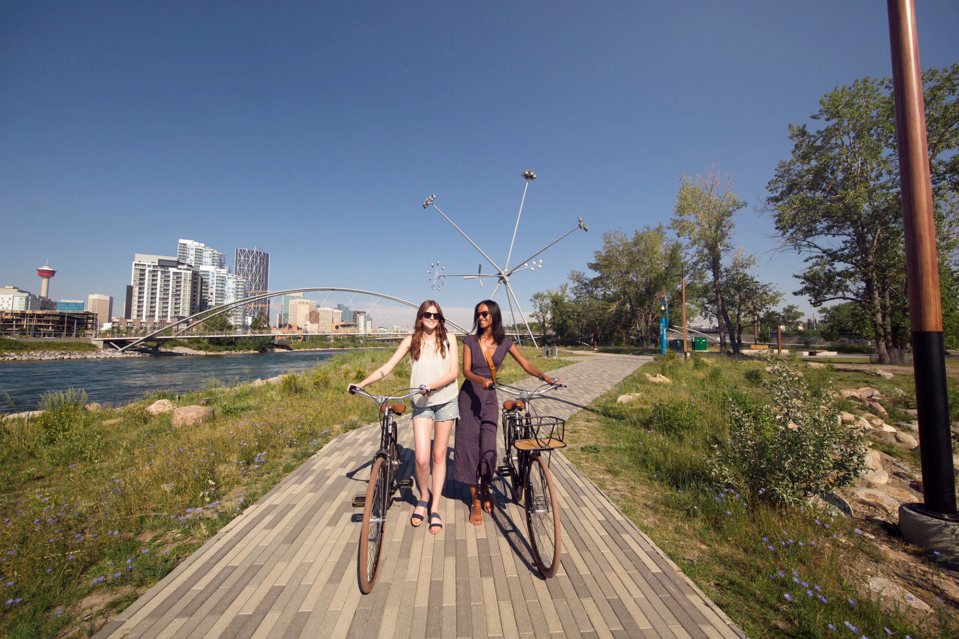 Two women walking their bikes on St. Patrick's Island in Calgary.